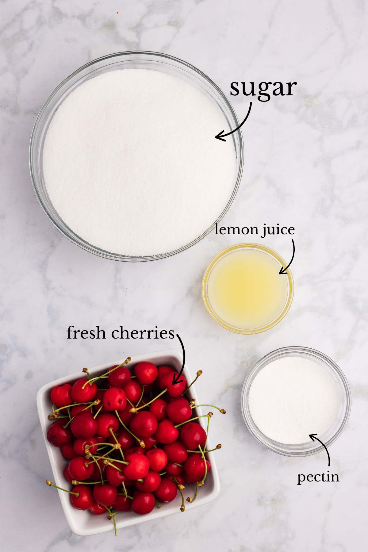 Ingredients for cherry jam including fresh cherries, sugar, lemon juice, and pectin in bowls.