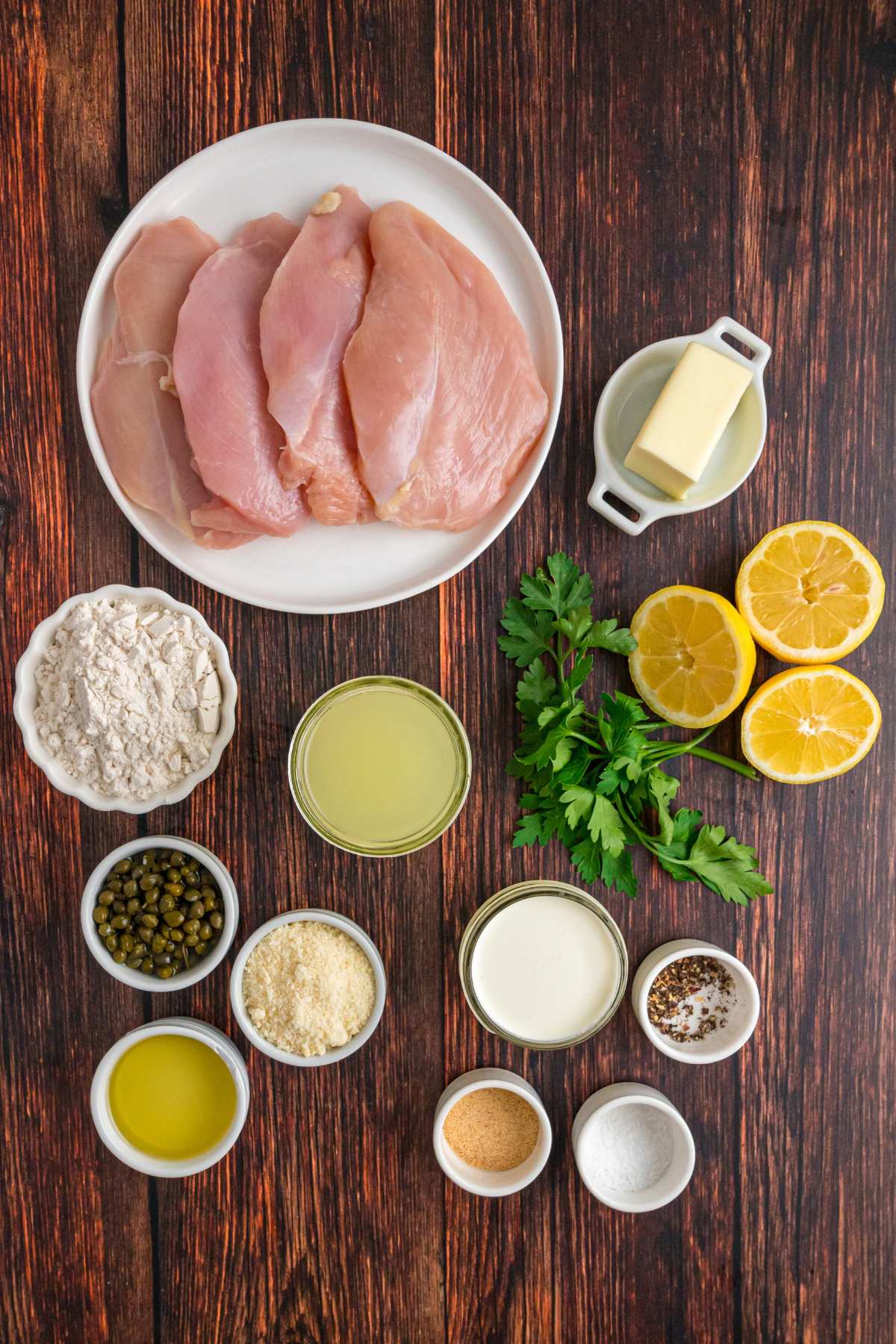 Raw chicken and other ingredients arranged on a wooden table.