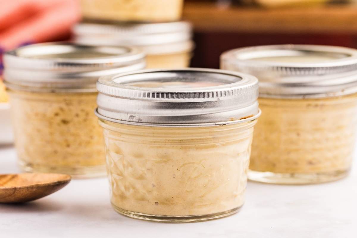 Several small glass jars filled with homemade Dijon mustard with metal lids.