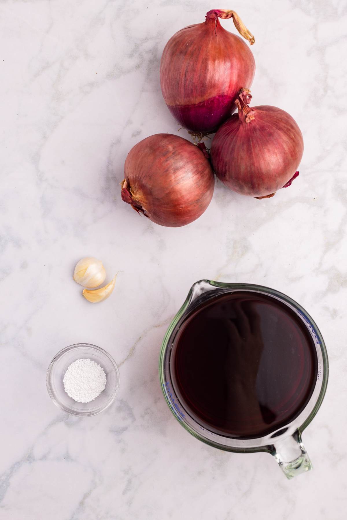 Red onions, garlic cloves, vinegar, pickle crisp arranged for recipe.