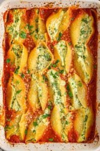 Baked stuffed shells in pan with sauce.
