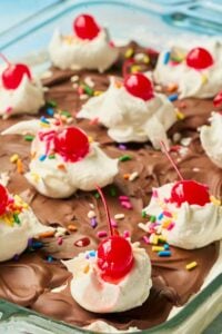 Overhead view of ice cream squares with chocolate, whipped cream and cherry toppings.