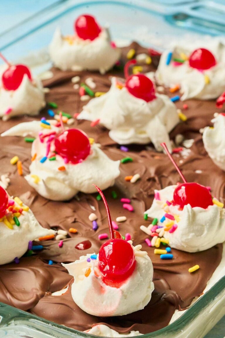 Overhead view of ice cream squares with chocolate, whipped cream and cherry toppings.