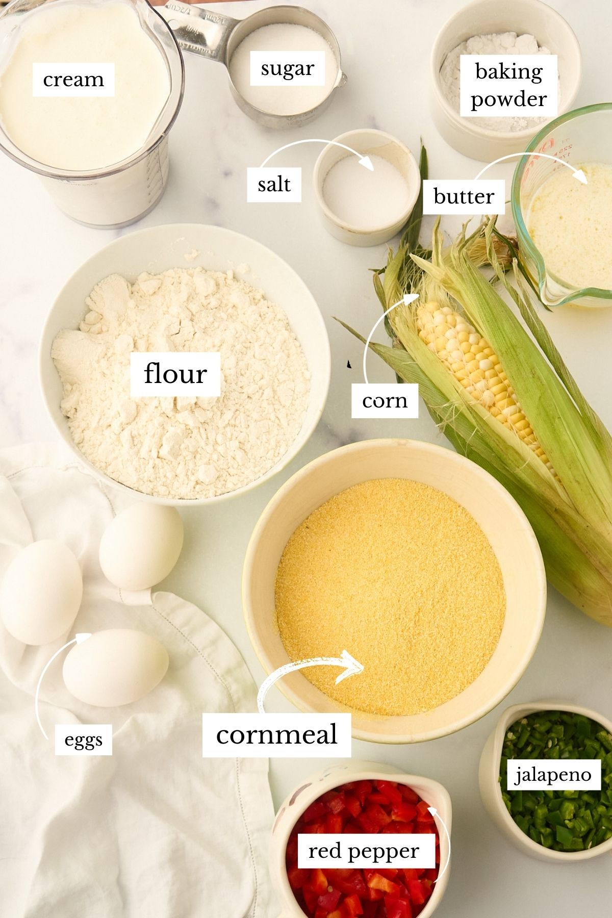 Ingredients for jalapeño cornbread muffins arranged on a white surface.