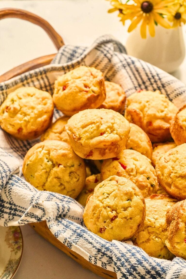 Basket of jalapeño cornbread muffins on a blue and white towel.