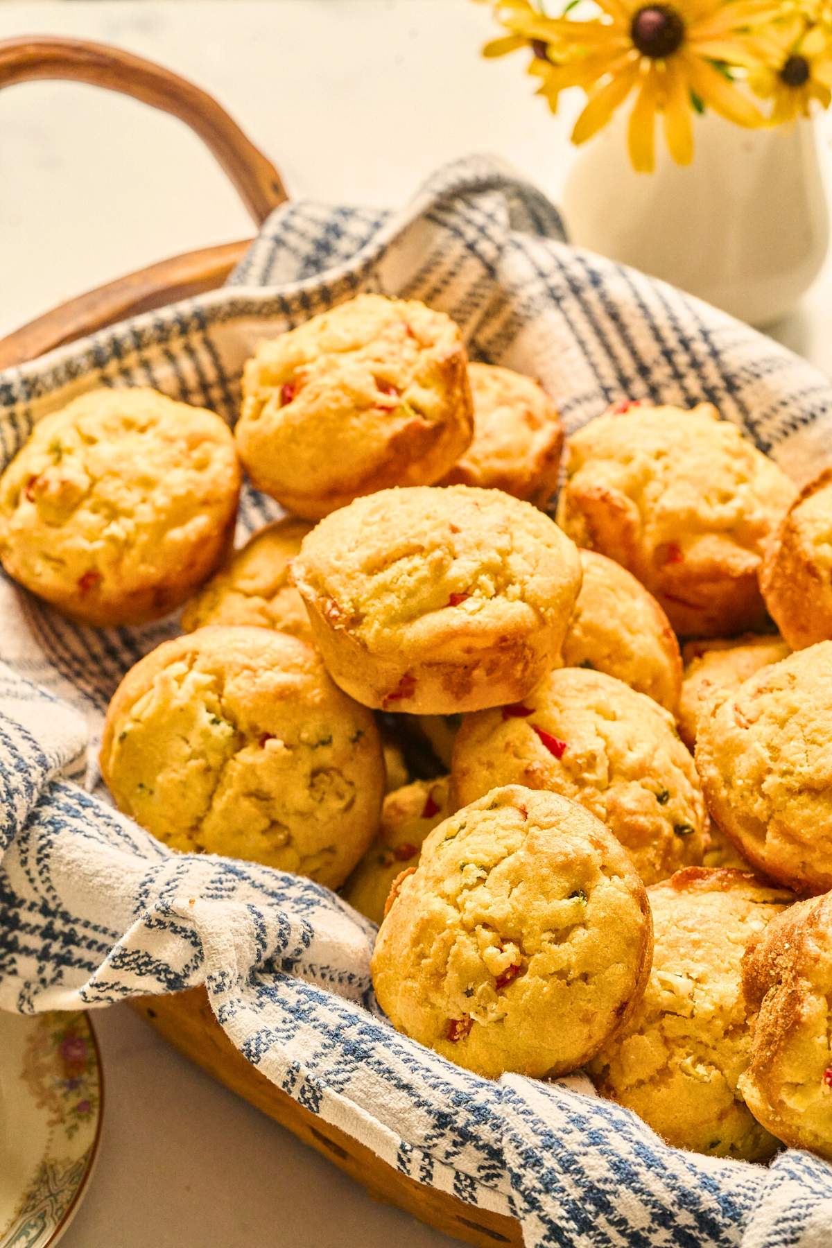 Basket of jalapeño cornbread muffins on a blue and white towel.