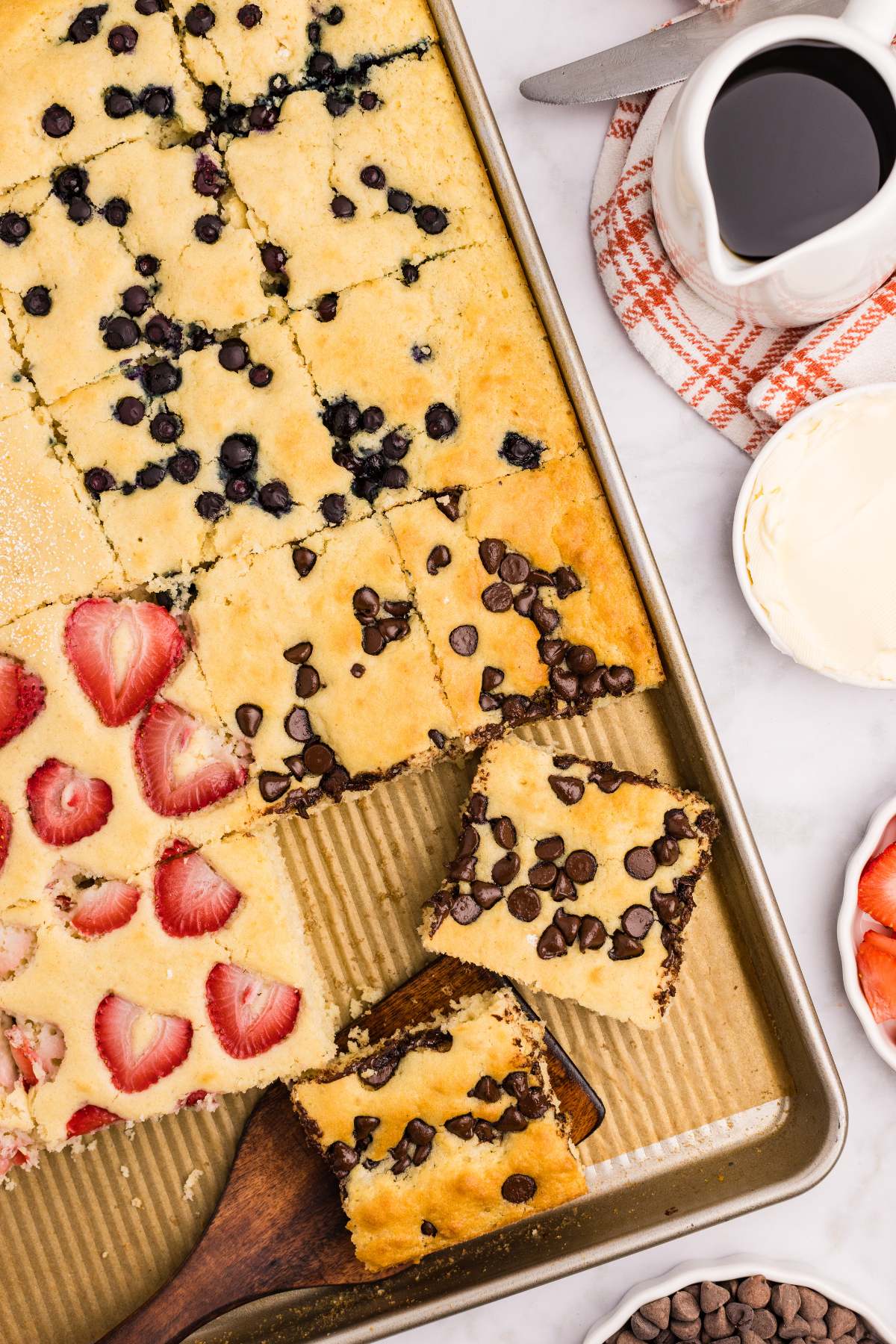 overhead view of sheet pan cakes with syrup nearby.