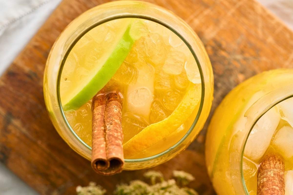Two glasses of autumn punch with apple slices and cinnamon sticks.