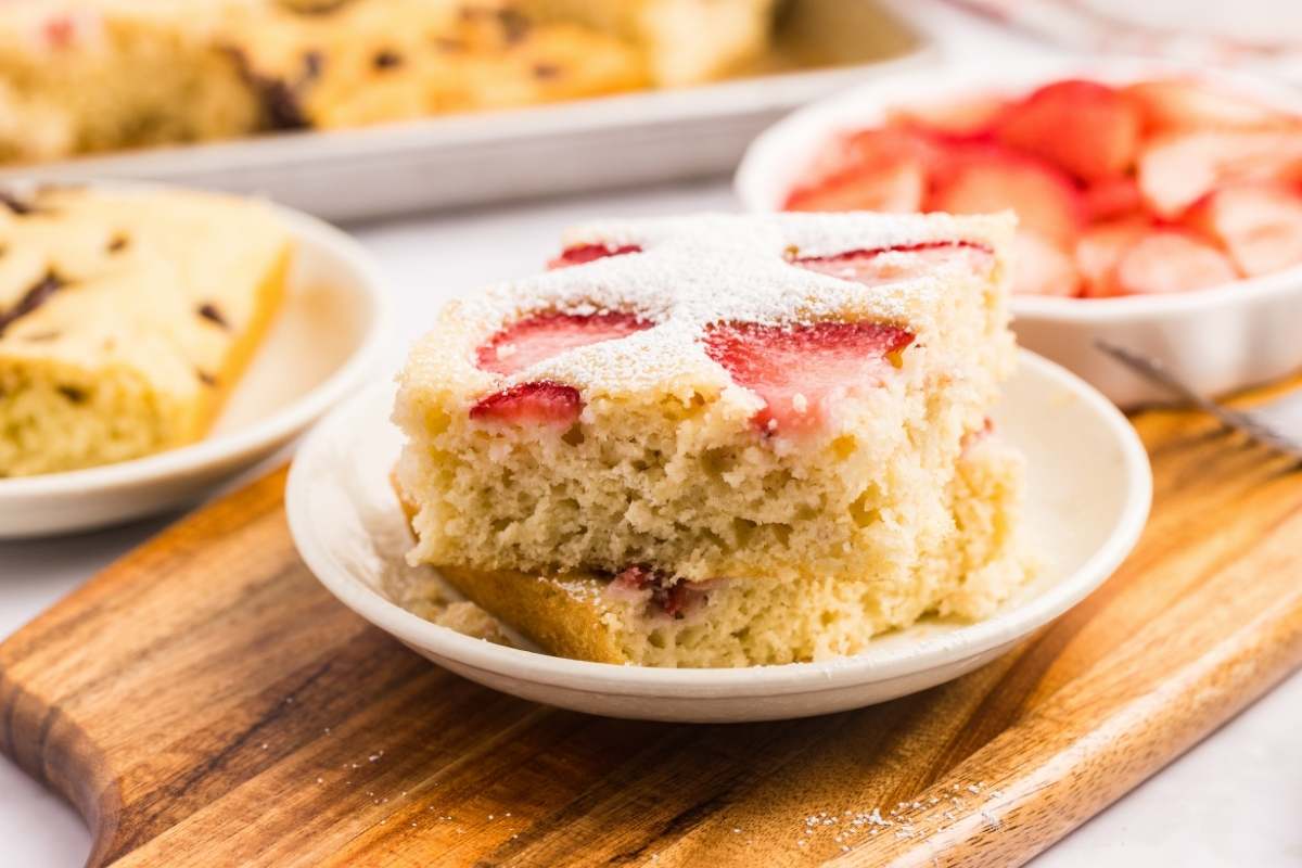 sliced sheet pan pancakes topped with strawberries and powdered sugar