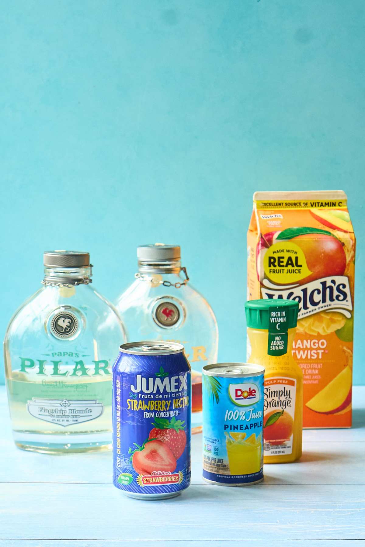  Rum bottles and tropical juice containers arranged on blue background.