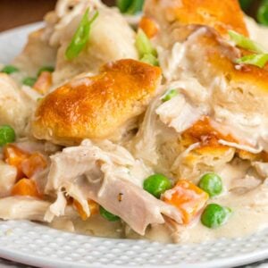 Close-up of chicken and biscuits with peas and carrots visible.