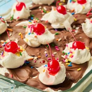 Angled view of ice cream squares in glass dish with chocolate and toppings.