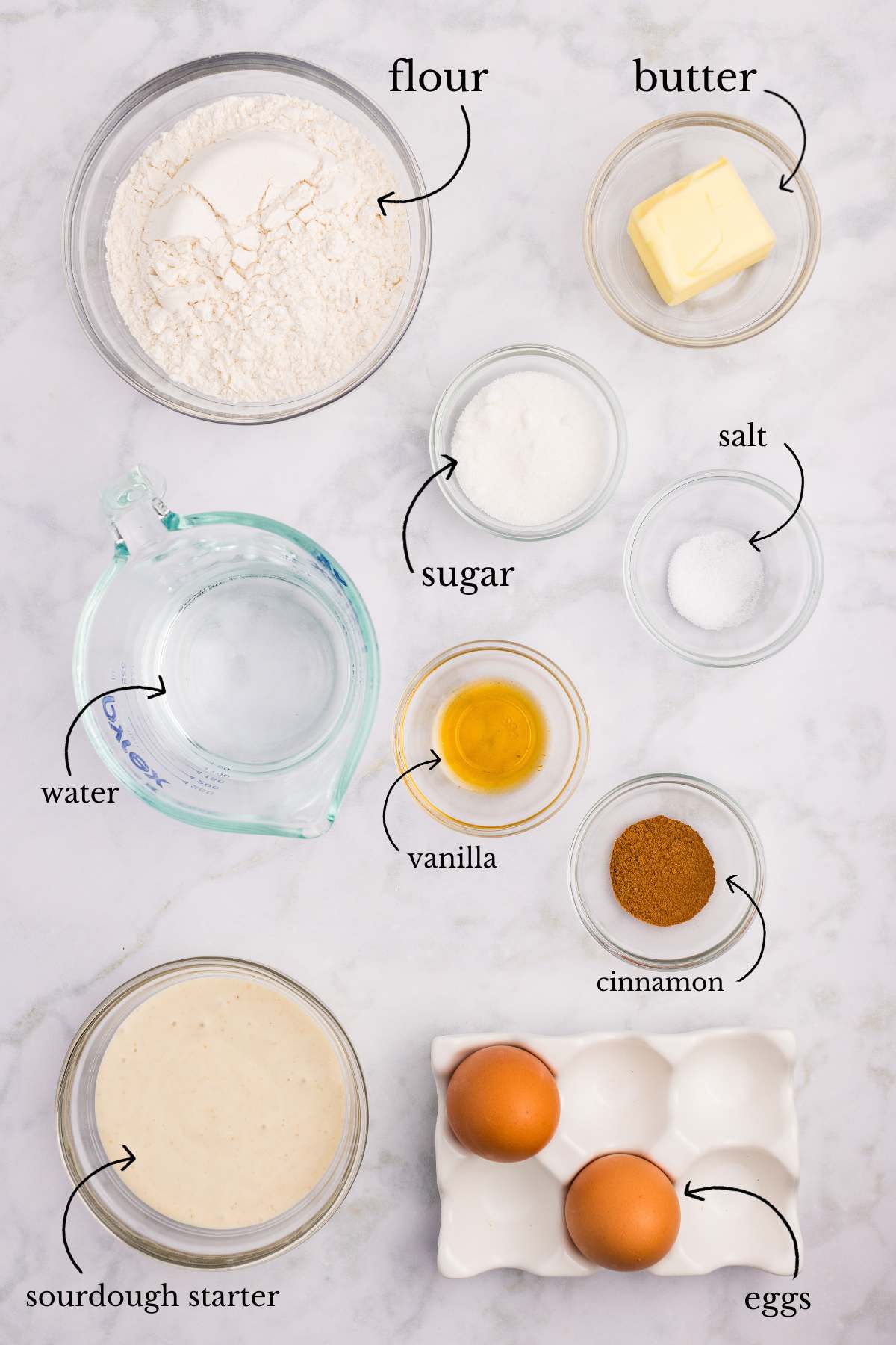 Labeled ingredients for churros including flour, butter, eggs, sourdough starter, and spices in bowls.