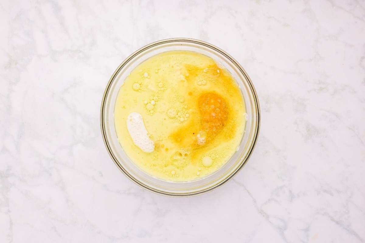  Bowl with beaten egg showing yellow yolk mixed with egg white.