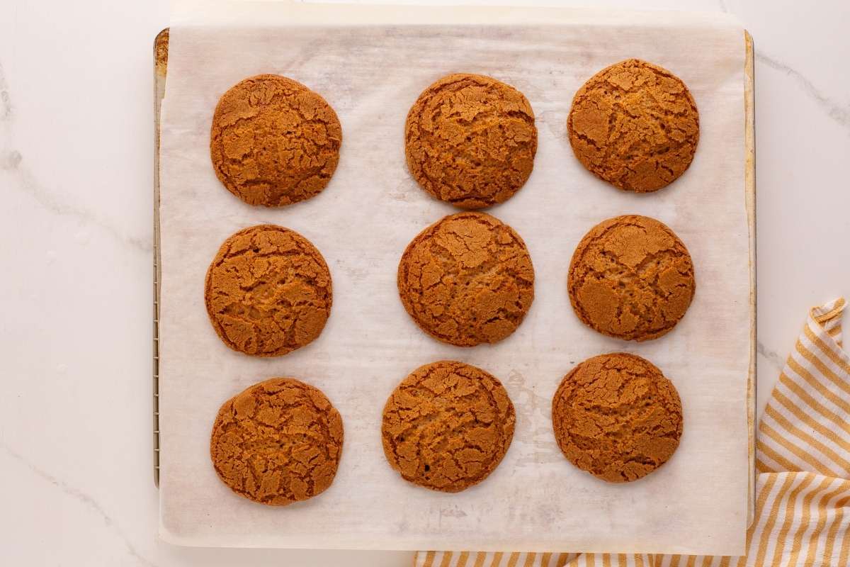 Nine baked molasses cookies on parchment-lined baking sheet.