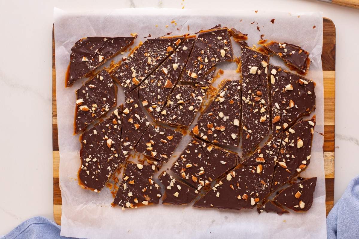 Broken pieces of chocolate almond toffee on parchment paper.