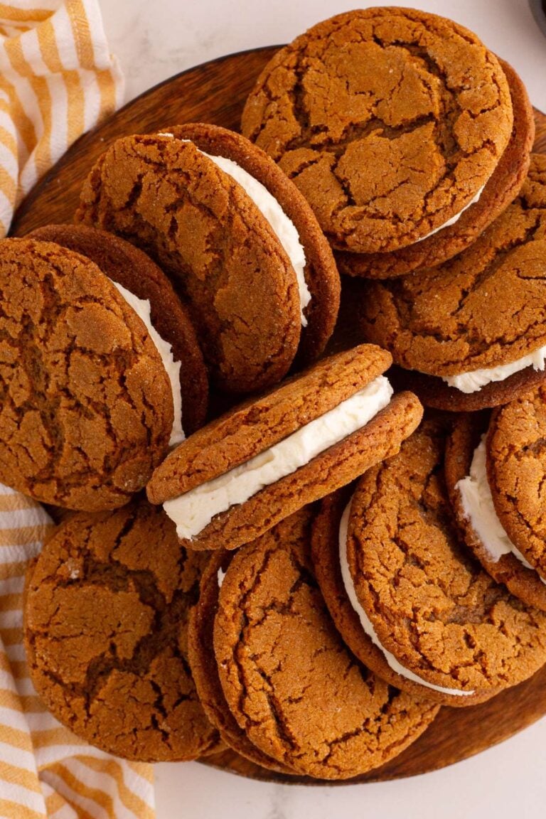 Molasses sandwich cookies piled on wooden plate.