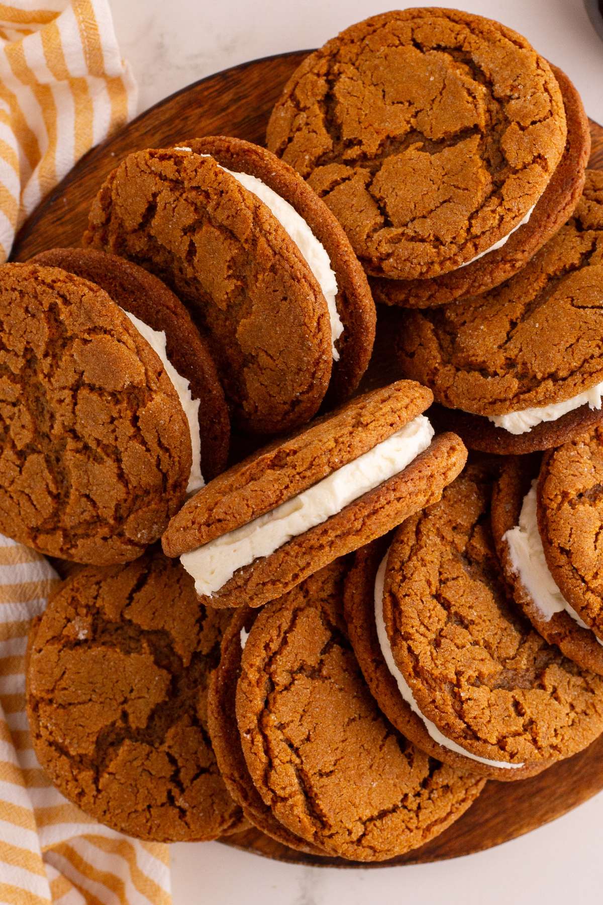 Molasses sandwich cookies piled on wooden plate.