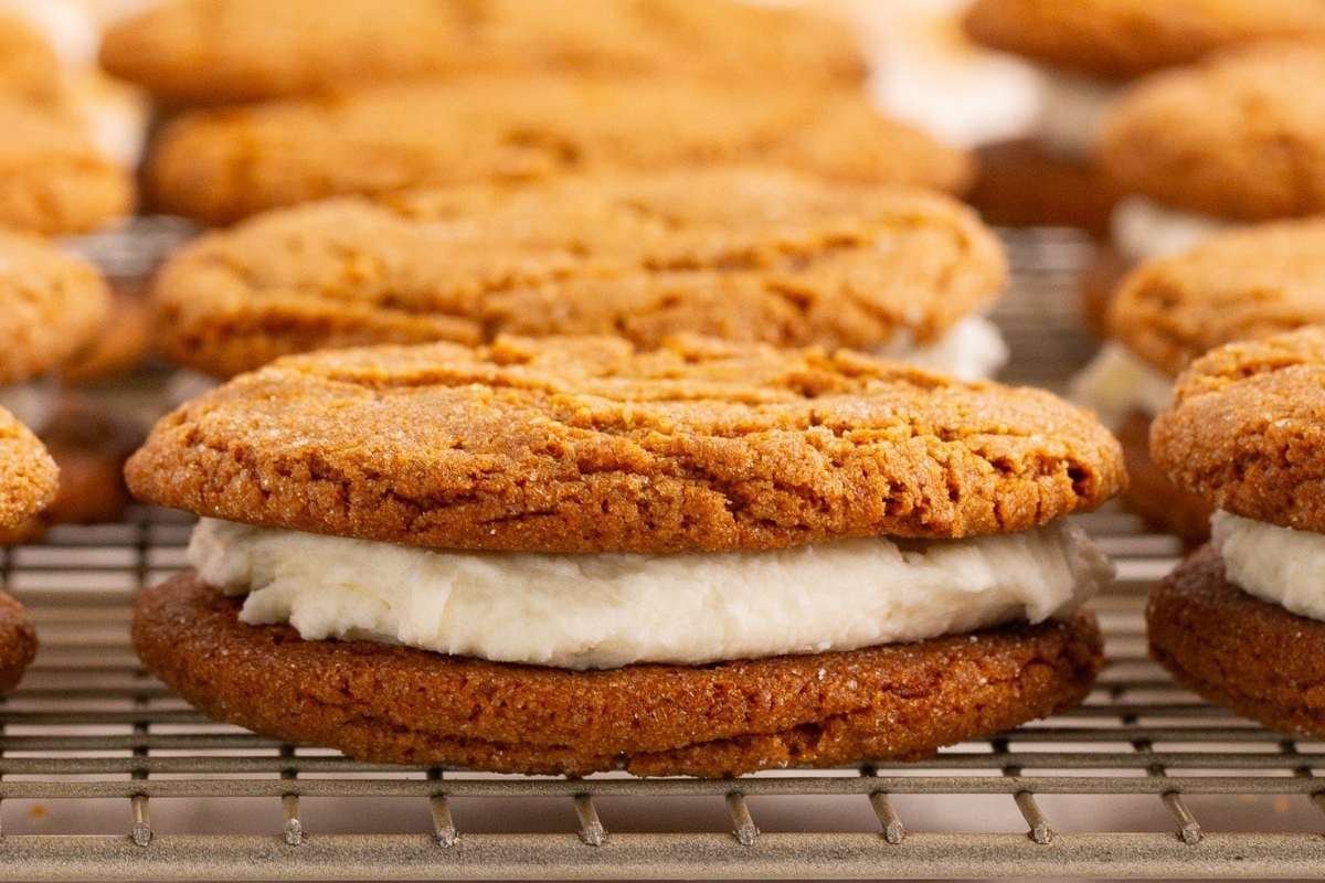 Molasses sandwich cookie on cooling rack with others behind.