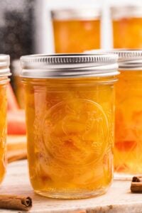 Several sealed mason jars filled with golden watermelon rind pickles on counter.