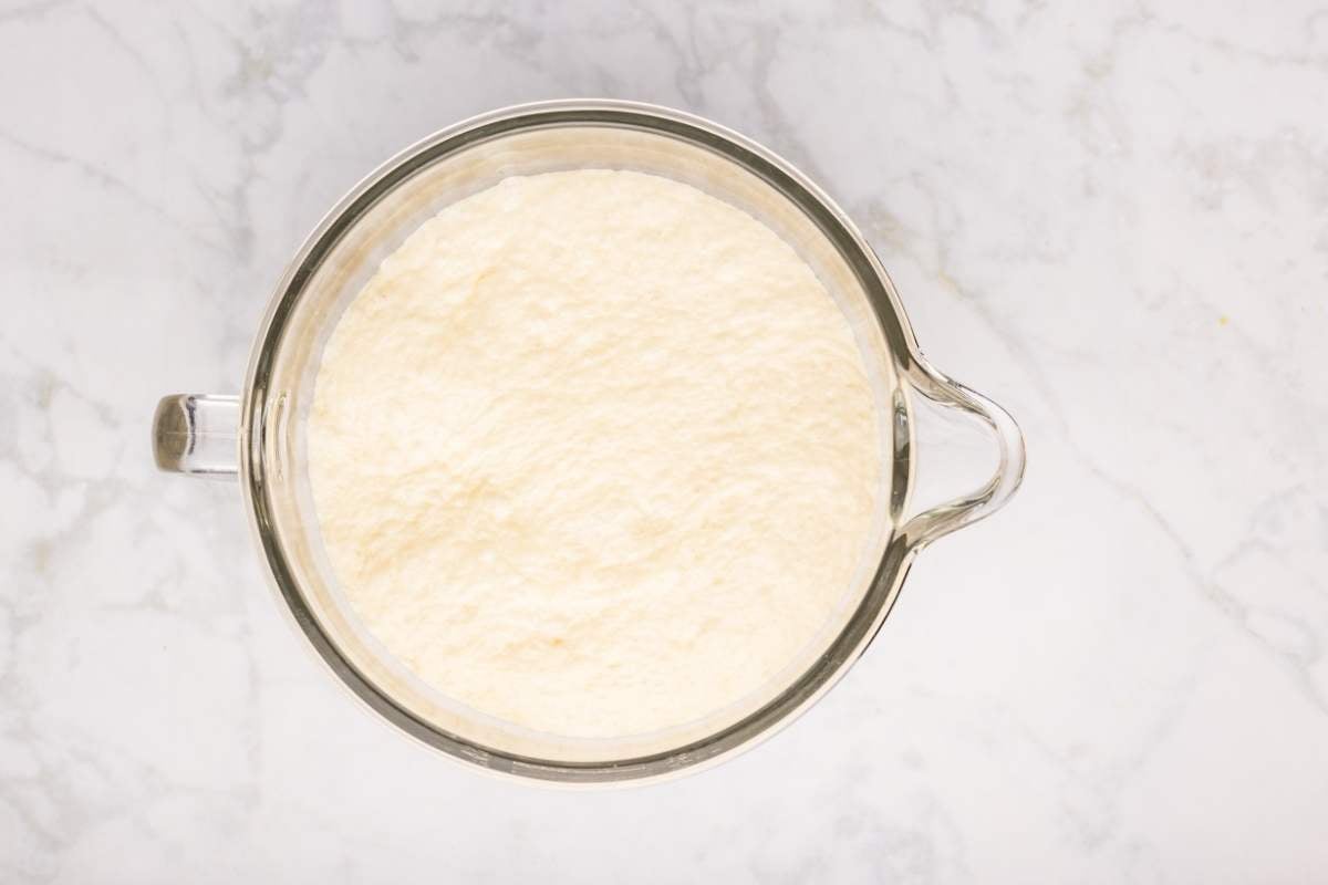 Dough doubled in size in a glass mixing bowl.