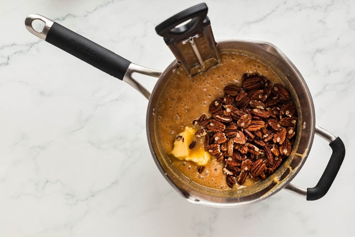 Butter and pecans added to hot syrup in saucepan.