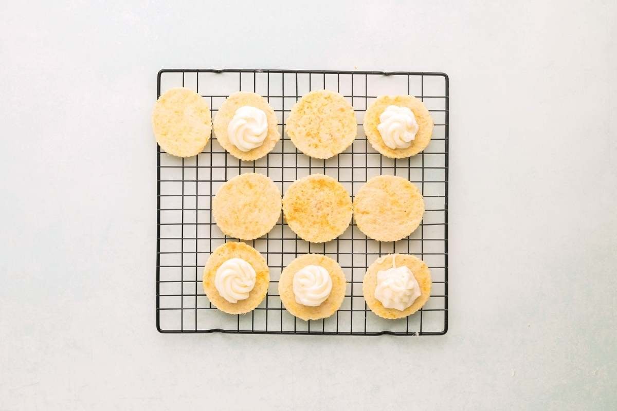 Cookies on cooling rack with buttercream being added to half.