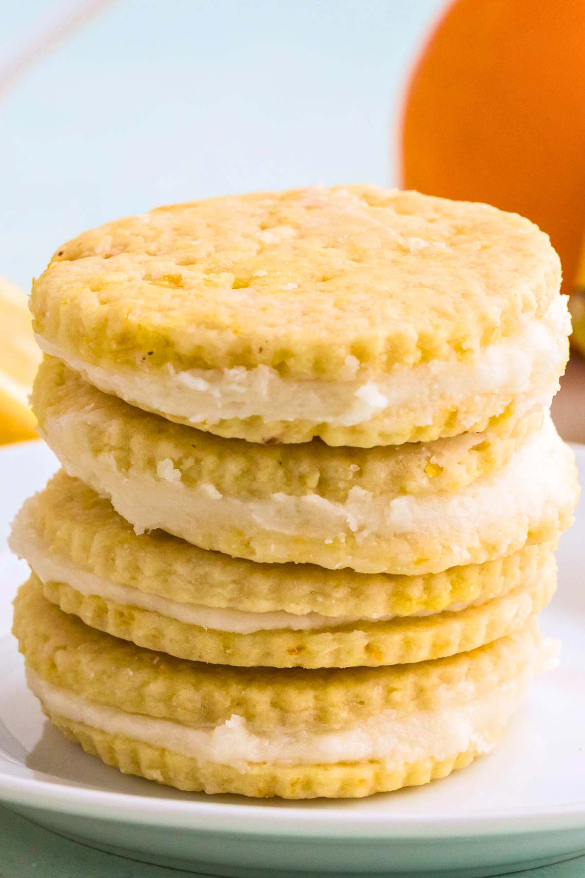 Stack of lemon shortbread sandwich cookies on a white plate.