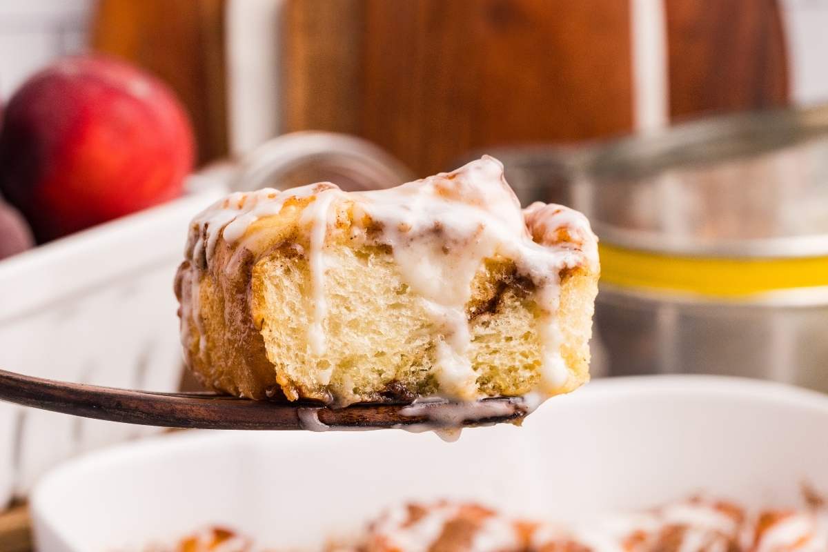 Single peach cobbler cinnamon roll on a wooden spatula.