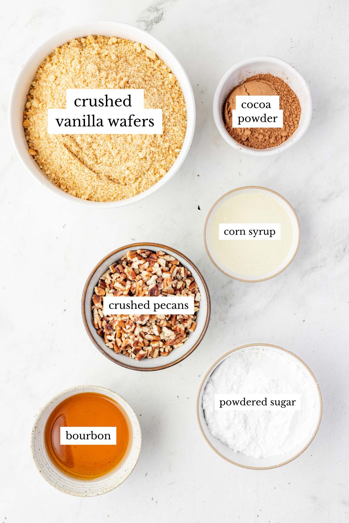 Ingredients in small bowls including wafers, pecans, cocoa, sugar, bourbon, and corn syrup.