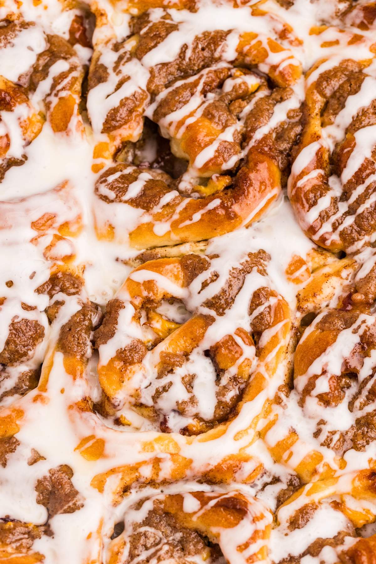Close-up of baked peach cobbler cinnamon rolls with icing drizzle