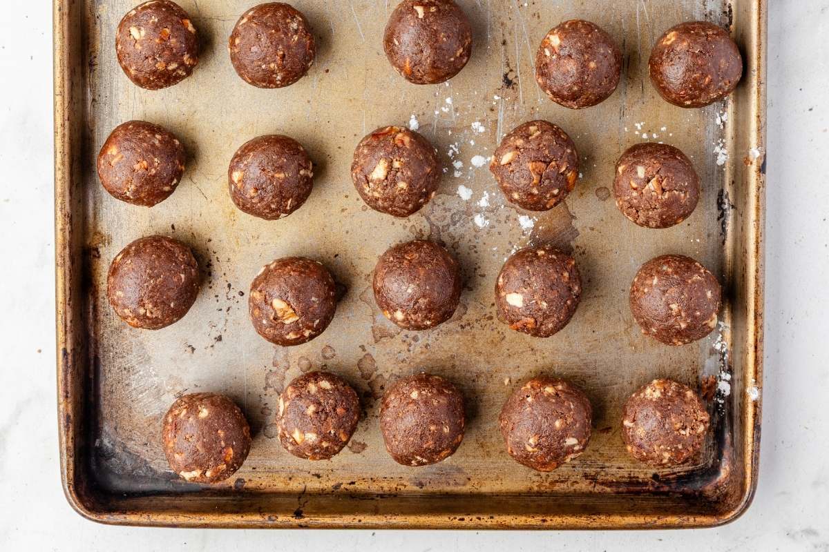 Uncoated bourbon balls lined up on a baking sheet.