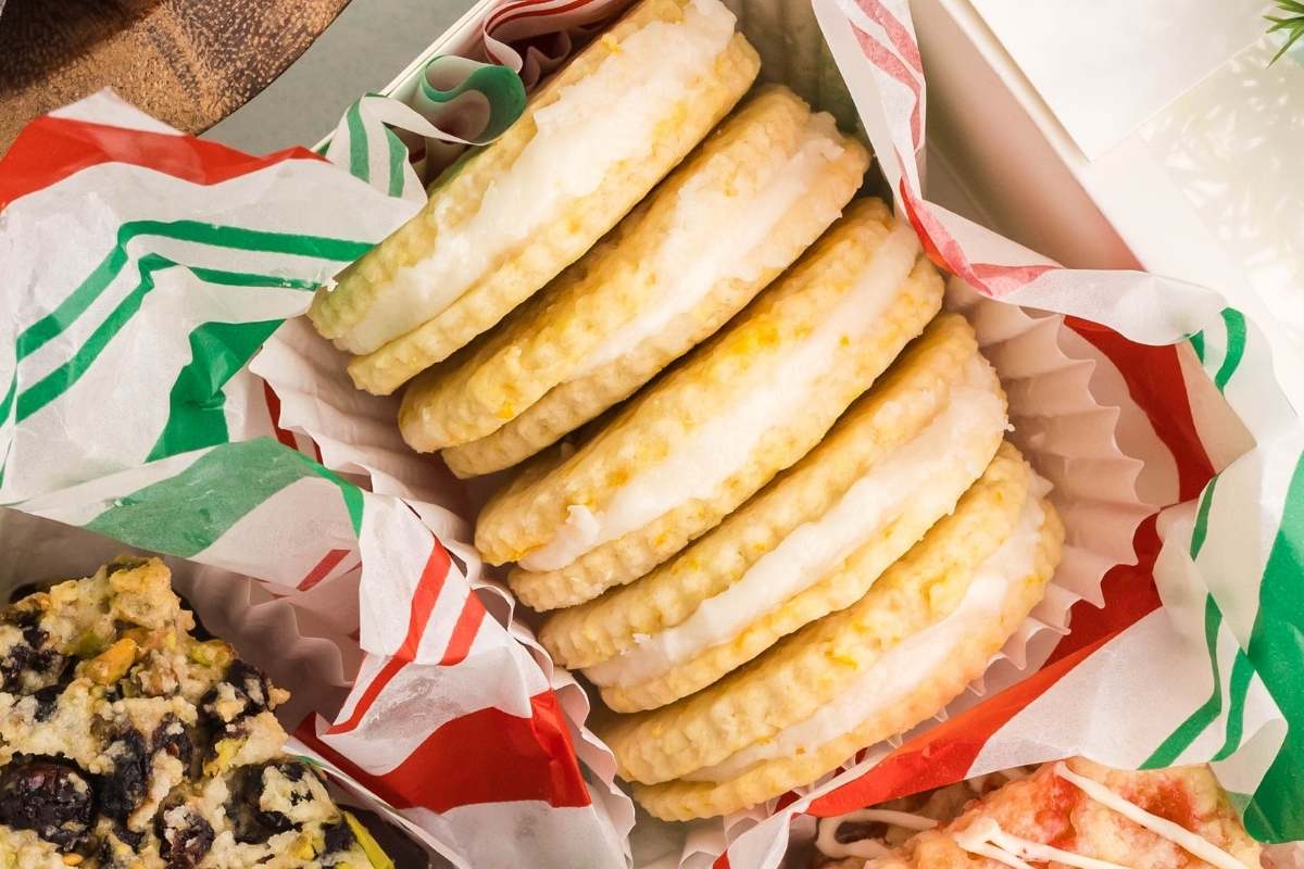 Stack of lemon sandwich cookies in paper-lined box.