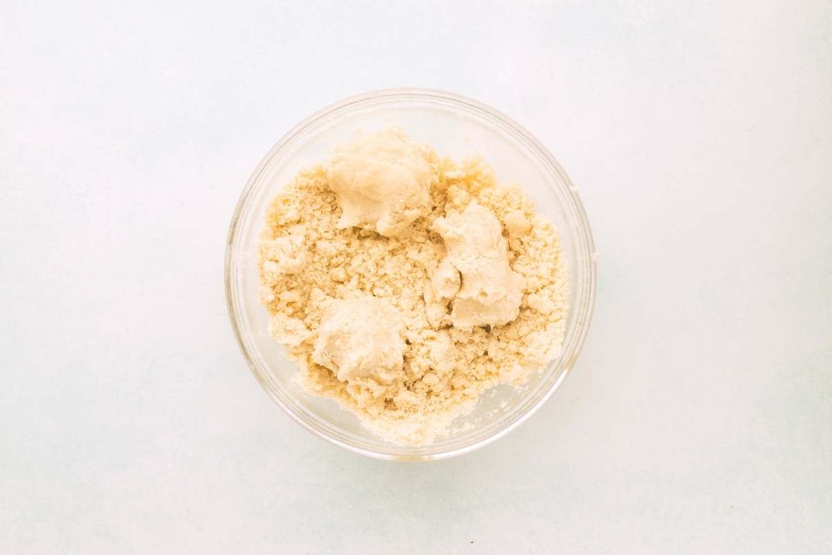 Crumbly lemon shortbread dough coming together in a glass bowl.
