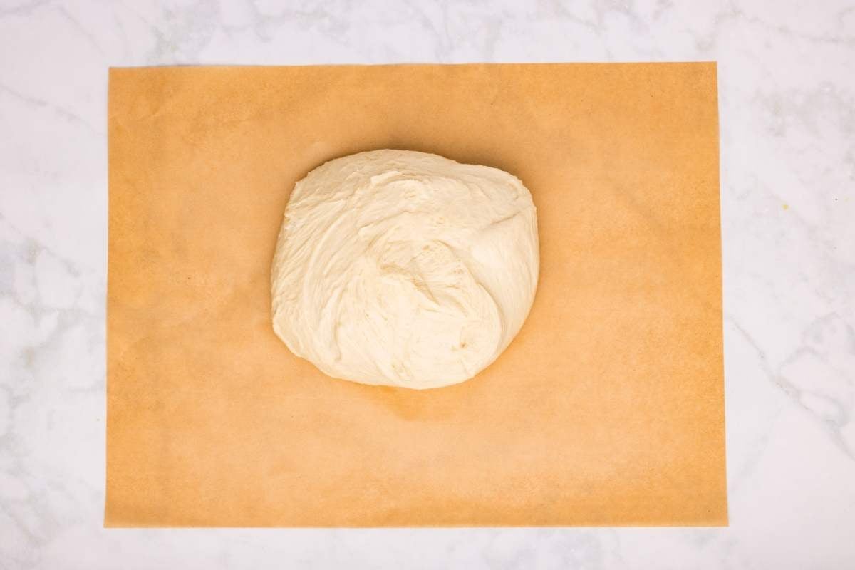Dough ball resting on a sheet of parchment paper.