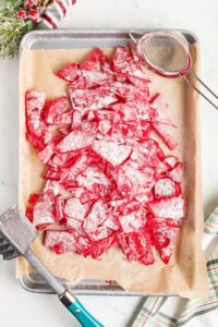Overhead view of homemade cinnamon candy on parchment-lined baking sheet.