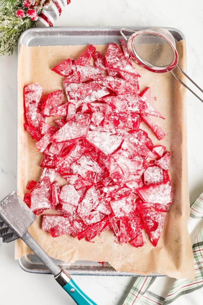 Overhead view of homemade cinnamon candy on parchment-lined baking sheet.