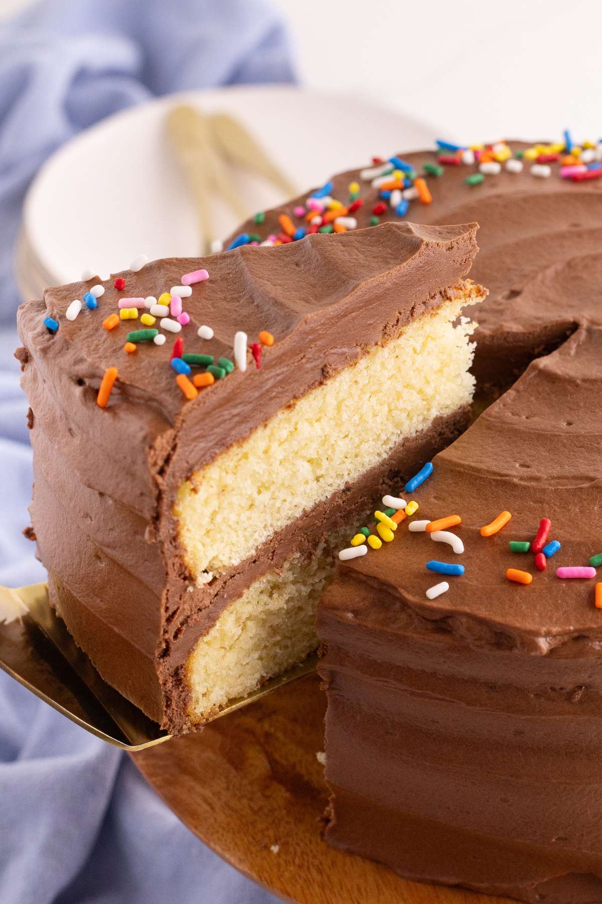Sliced yellow cake showing moist layers and thick chocolate frosting filling.