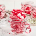 glass jar with shards of red candy on white background.