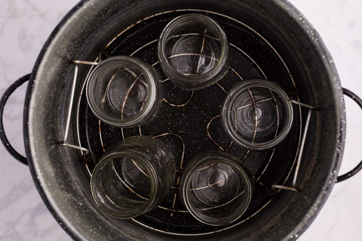 Canned jars cooling on a towel next to a canning pot.