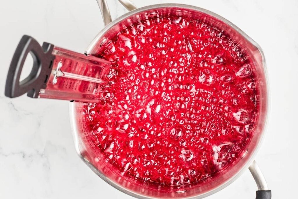 Saucepan with bubbling red liquid, overhead view.