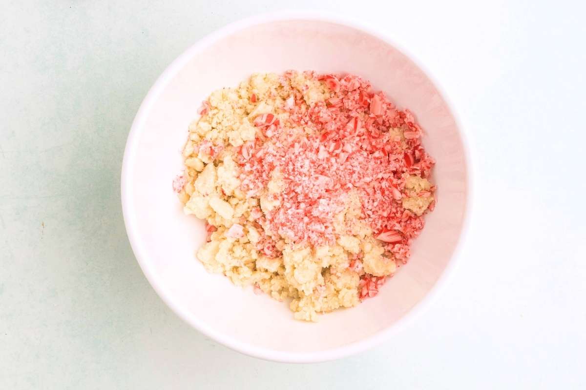 Shortbread dough mixed with crushed candy canes in a bowl.