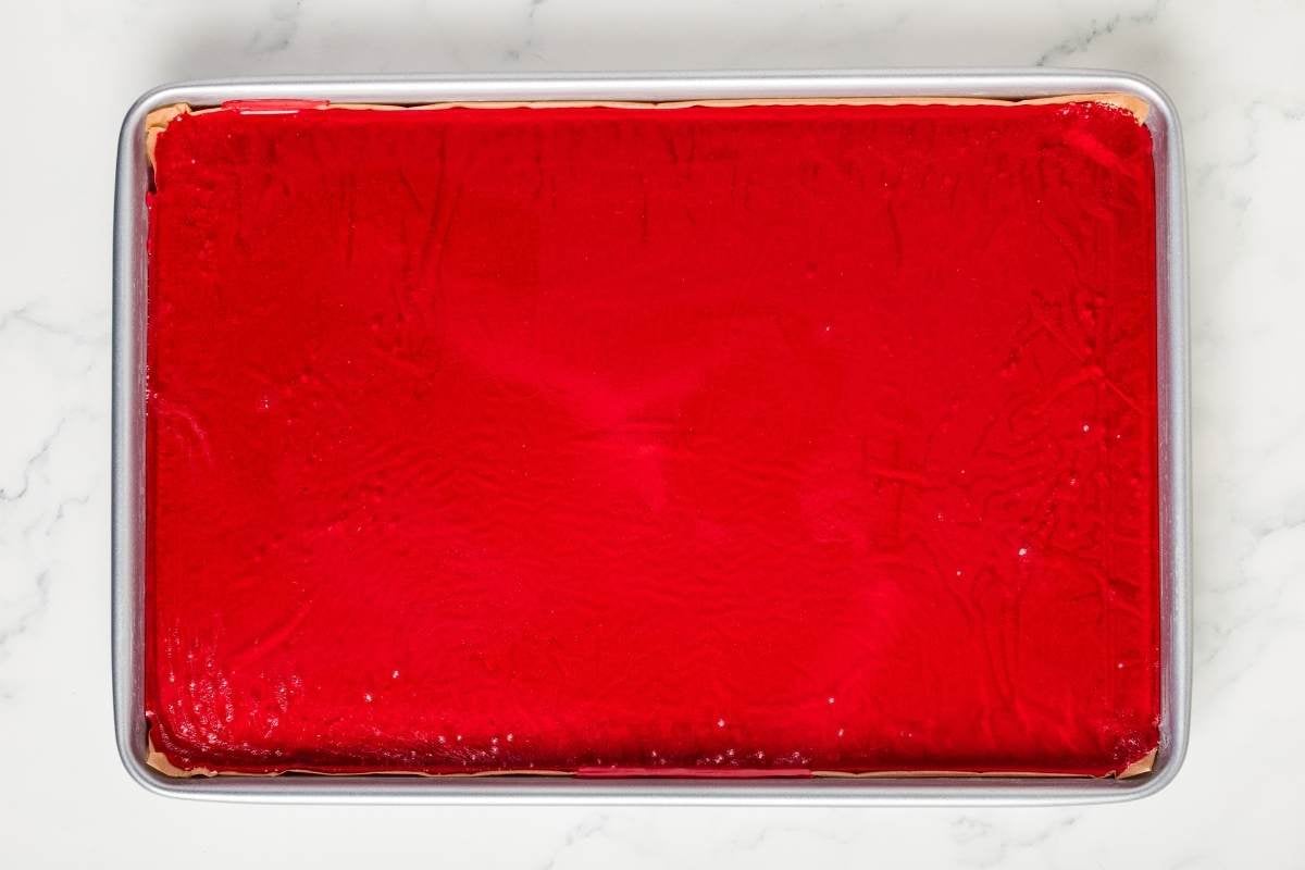 Rimmed baking sheet filled with clear, red, hard candy.
