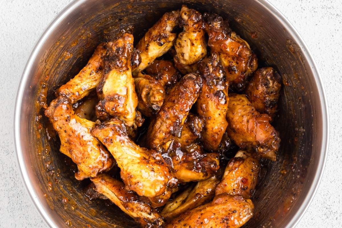 Large metal mixing bowl with wings, tossed and glazed.