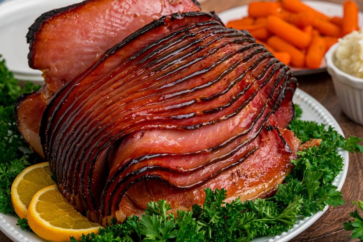 Finished ham on a wooden counter with sides and background.