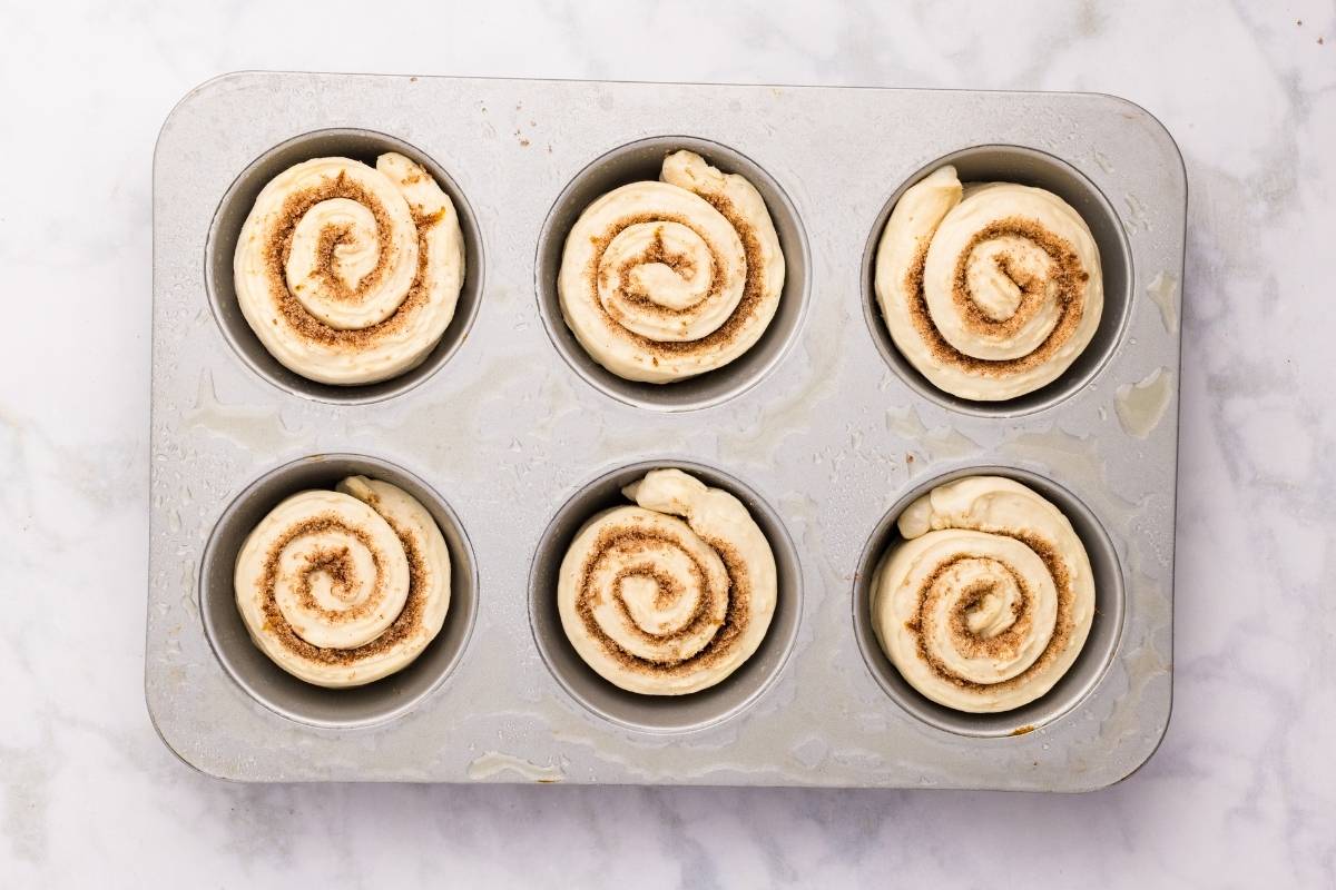 Proofed buns in muffin tins.