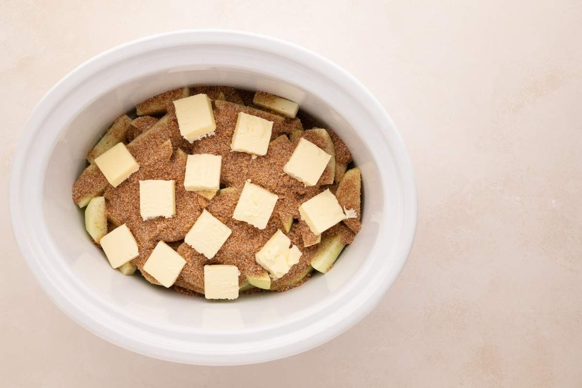 pats of butter on top of sugar mixture and sliced apples.