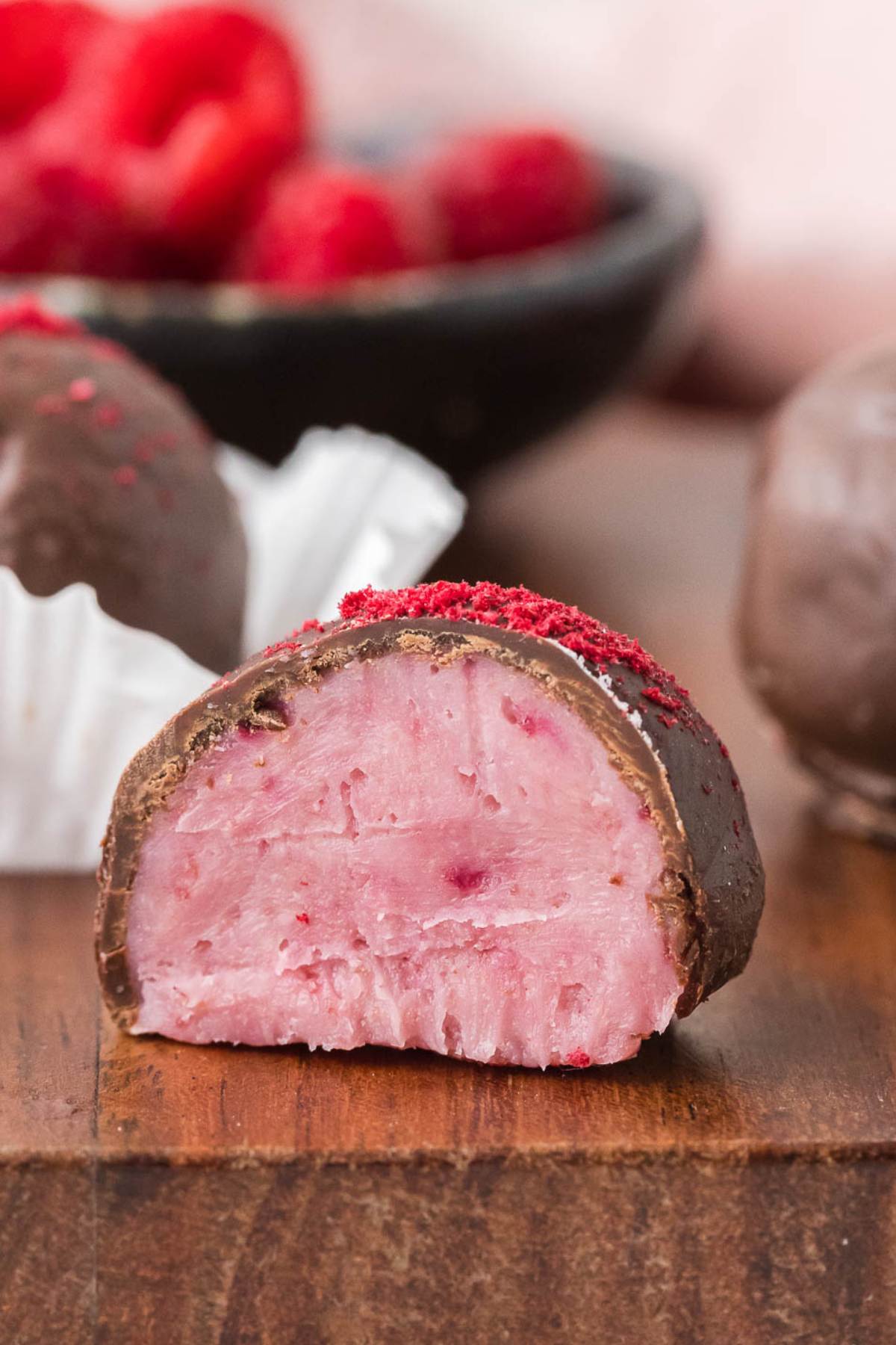 finished truffle cut in half showing pink filling and chocolate coating.