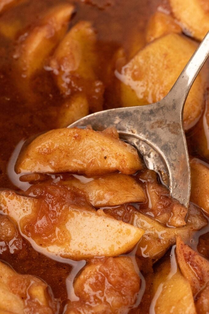 close up of apples in slow cooker being scooped out.