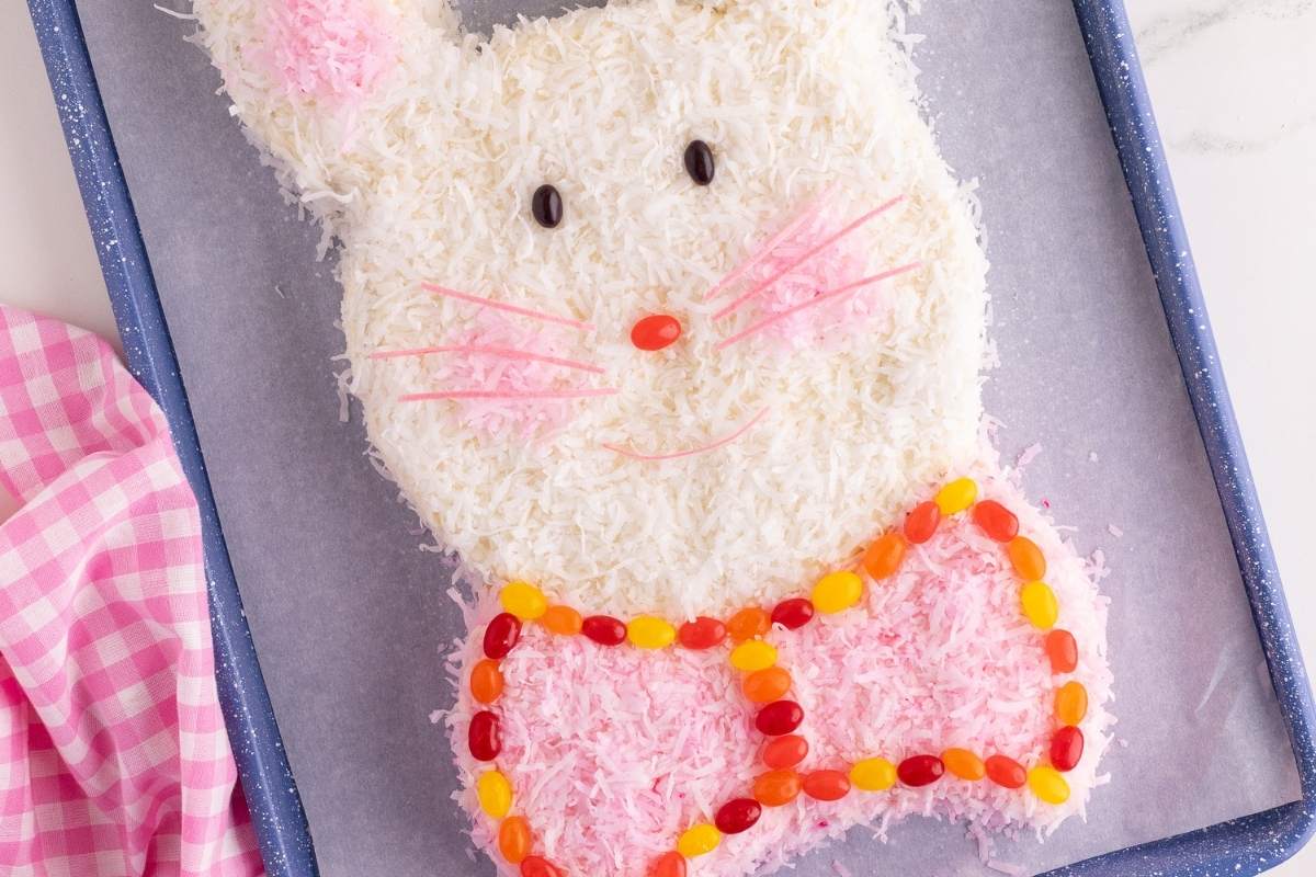 Overhead view of a coconut bunny cake with jellybean bowtie and pink whiskers.